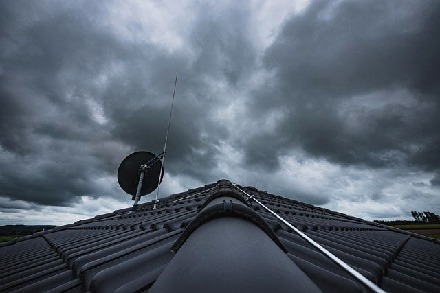 Blitzableiter auf einem Dach, höher als die Satellitenschüssel Blitzableiter auf einem Dach, höher als die Satellitenschüssel